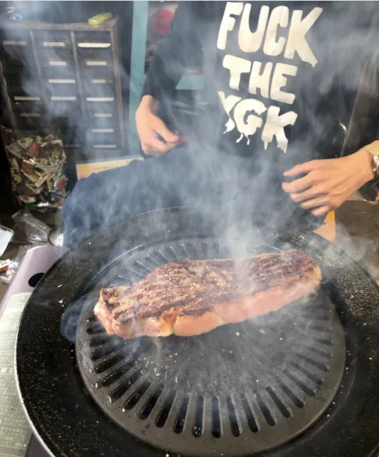 店長が鉄板で肉を焼いているバーベキューの様子